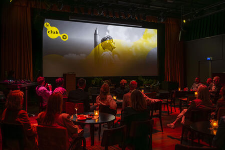 Een prijsuitreiking in een sfeervolle zaal met een groot scherm, waar een presentatie op wordt getoond.