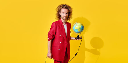 Man in een rode suit houdt een globe vast voor een heldergele achtergrond.