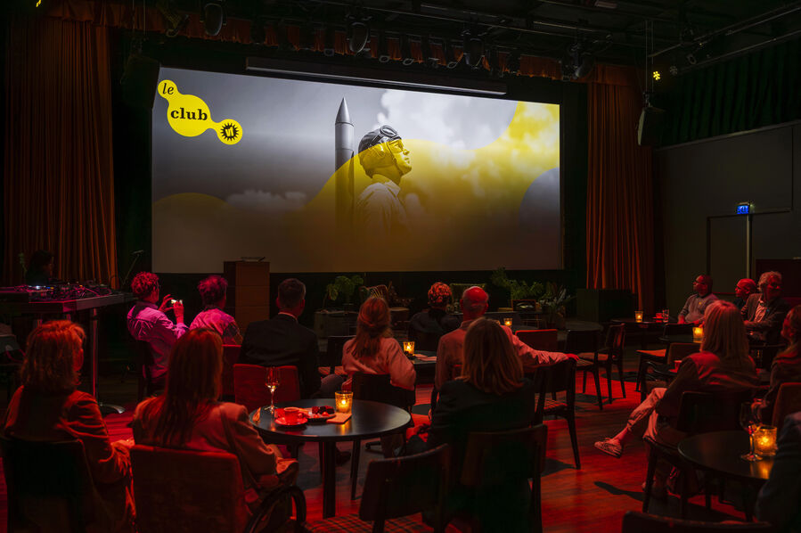 Een prijsuitreiking in een sfeervolle zaal met een groot scherm, waar een presentatie op wordt getoond.