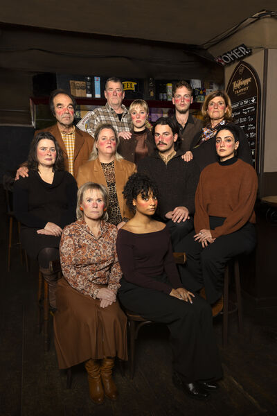 Groep mensen poseert samen in een café, glimlachend en in casual kleding.