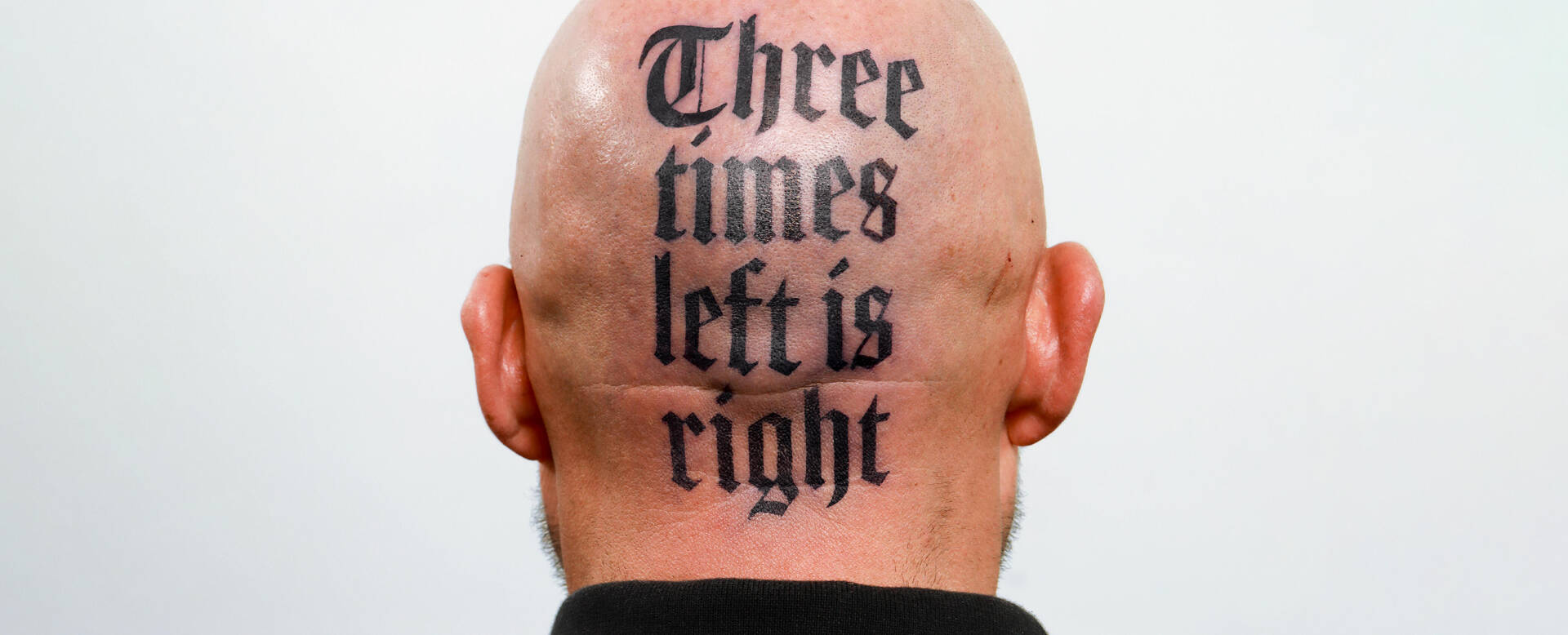 Bald head with a tattoo on the back reading: "Three times left is right."
