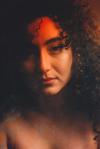 Portret van een vrouw met krullend haar, zachte belichting en een dromerige uitstraling.