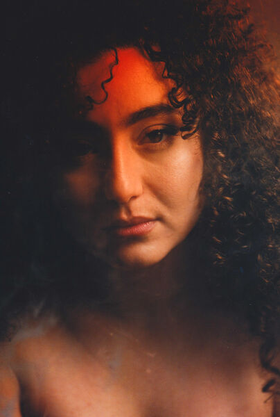 Portret van een vrouw met krullend haar, zachte belichting en een dromerige uitstraling.