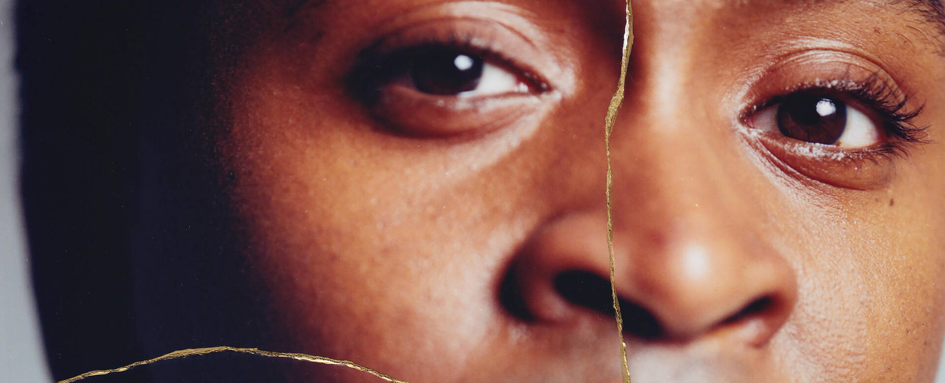 Een close-up van een gezicht met nadruk op de ogen en huidtextuur, met een artistieke scheiding in het midden.